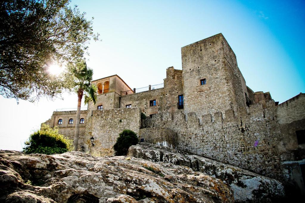 un viejo castillo con un árbol delante de él en Hotel Tugasa Castillo de Castellar en Castellar de la Frontera