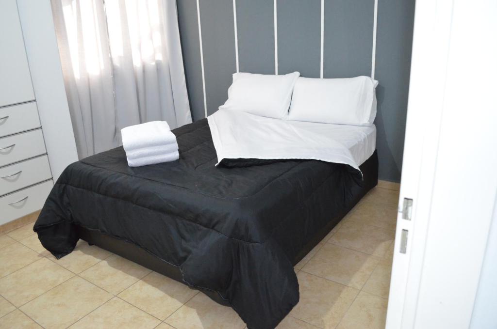 a bedroom with a bed with black sheets and white pillows at Complejo Fatima in Villa Dolores