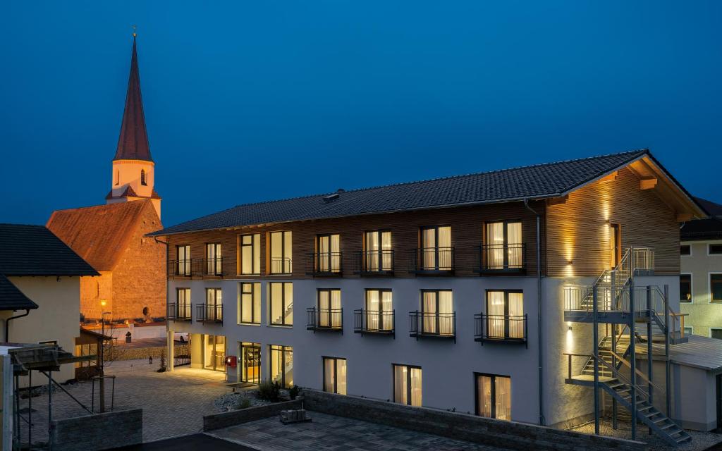 ein großes Gebäude mit einer Kirche im Hintergrund in der Unterkunft Hotel Traumschmiede in Unterneukirchen