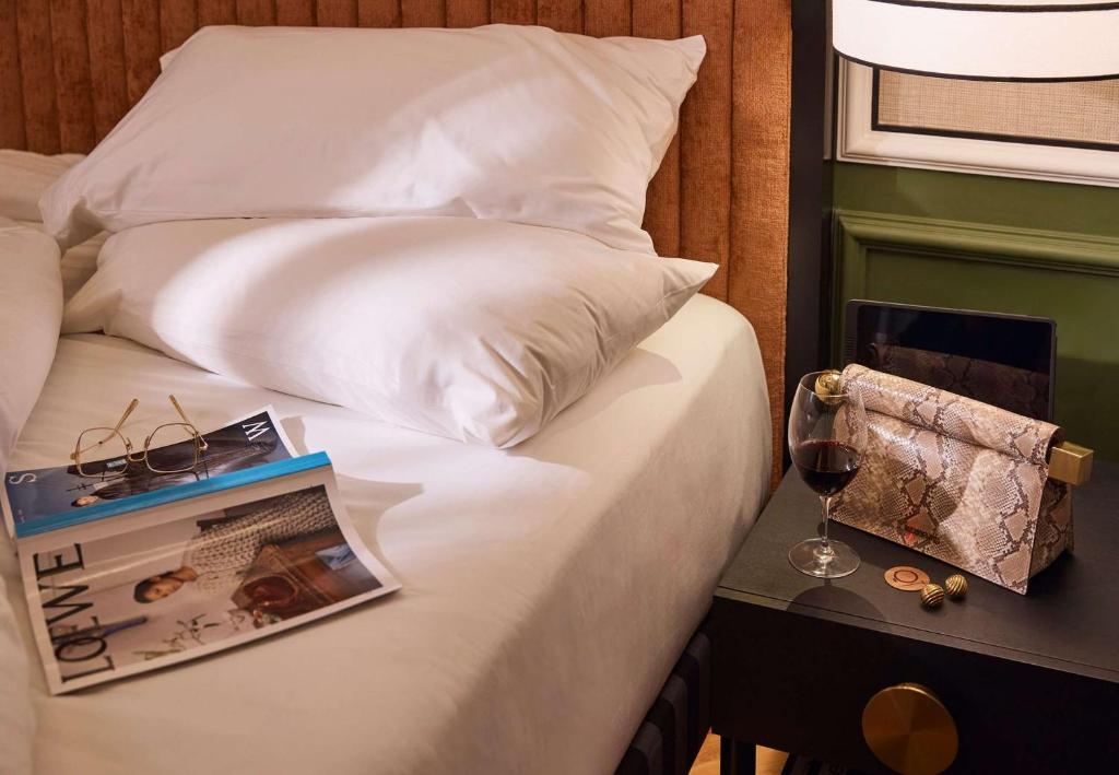 a bed with a book and a glass of wine at QT Singapore in Singapore