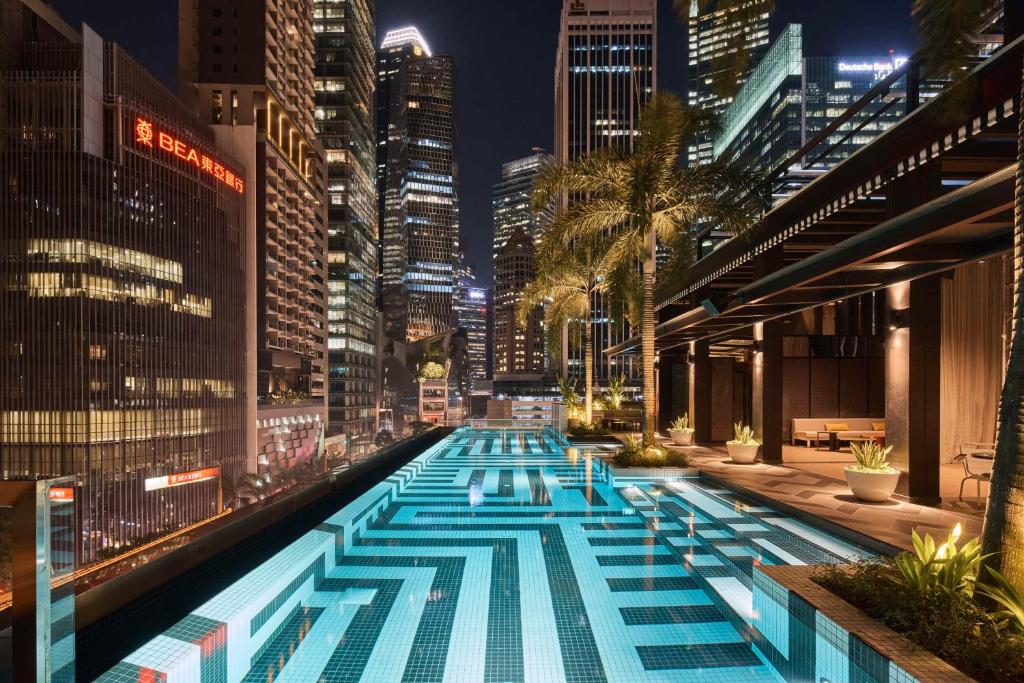 a pool in the middle of a city at night at QT Singapore in Singapore
