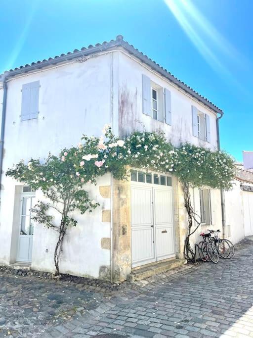 Un bâtiment blanc avec des fleurs sur son côté dans l'établissement Maison de ville Chai Saint Martin de Ré, à Saint-Martin-de-Ré