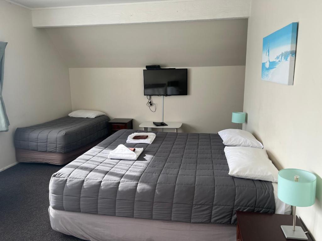 a bedroom with two beds and a flat screen tv at Drury Motor Lodge in Drury