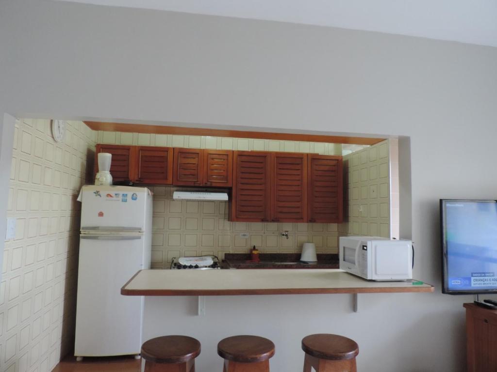 a kitchen with a white refrigerator and wooden cabinets at Apartamento Praia Grande in Ubatuba