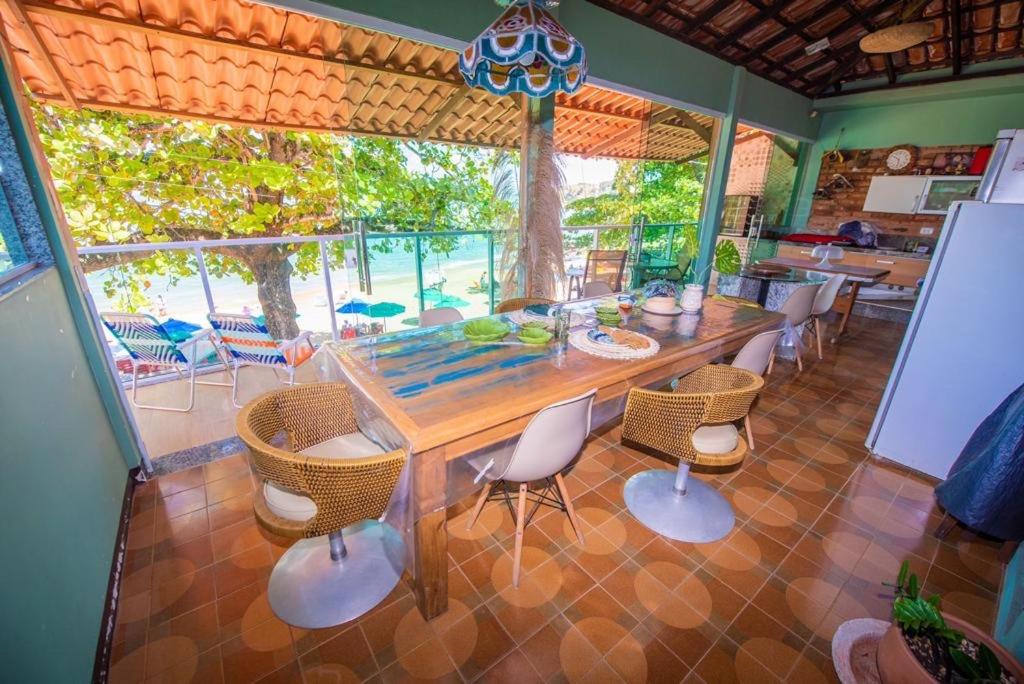 a dining room with a wooden table and chairs at Casa com os pés no mar em Iriri ES in Anchieta