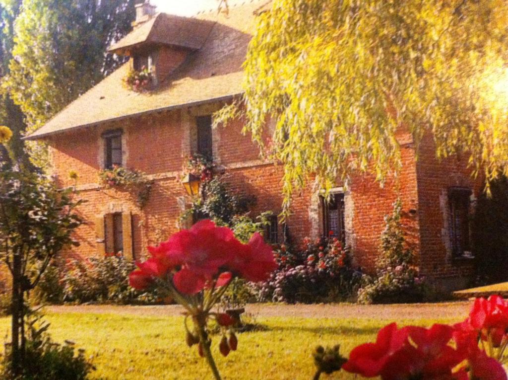 une maison en briques avec des fleurs devant elle dans l'établissement La Ferme Des Vignes, à Hotot-en-Auge