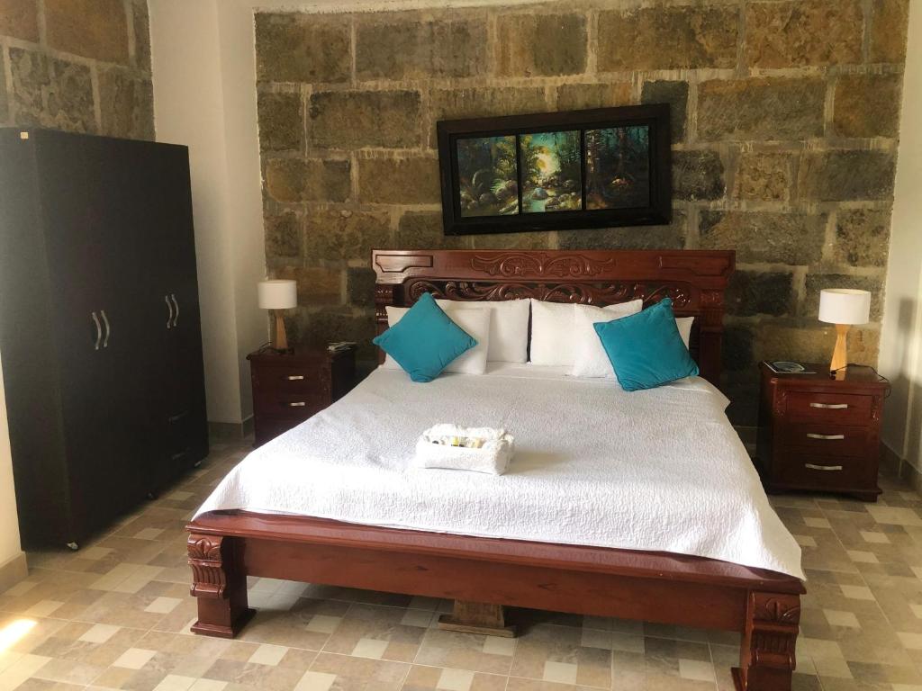 a bedroom with a large bed with blue pillows at Hotel Hacienda Guane Urbano in Oiba