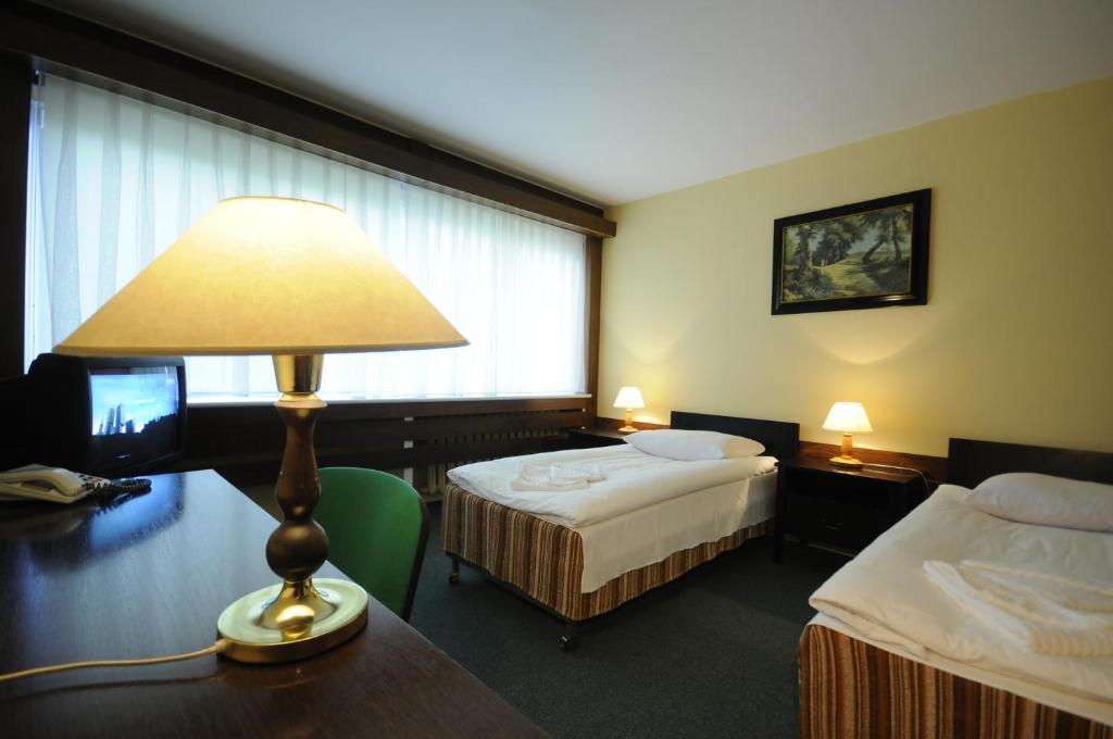 a hotel room with two beds and a table with a lamp at Olimpia in Poznań