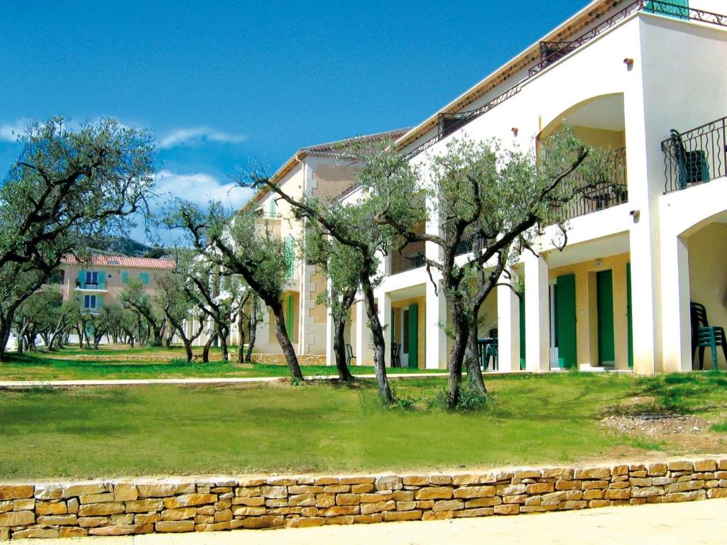 un bâtiment blanc avec des arbres devant dans l'établissement Apartment in Provence near Alpilles, à Paradou