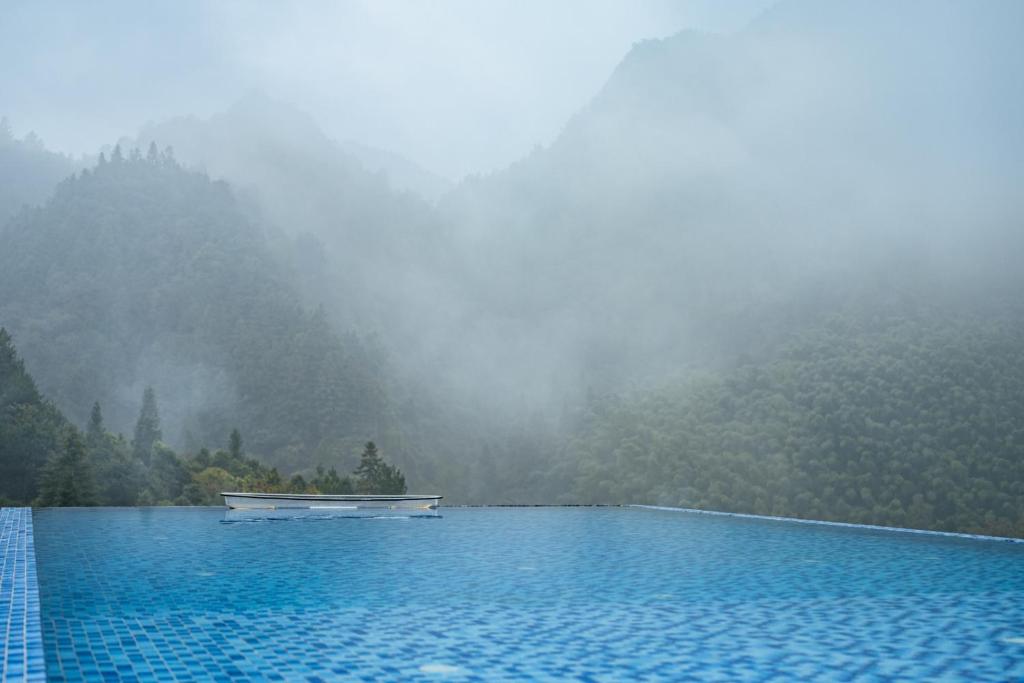 a boat in a swimming pool in front of a mountain at Pandora's Hilltop House Resort in Zhangjiajie