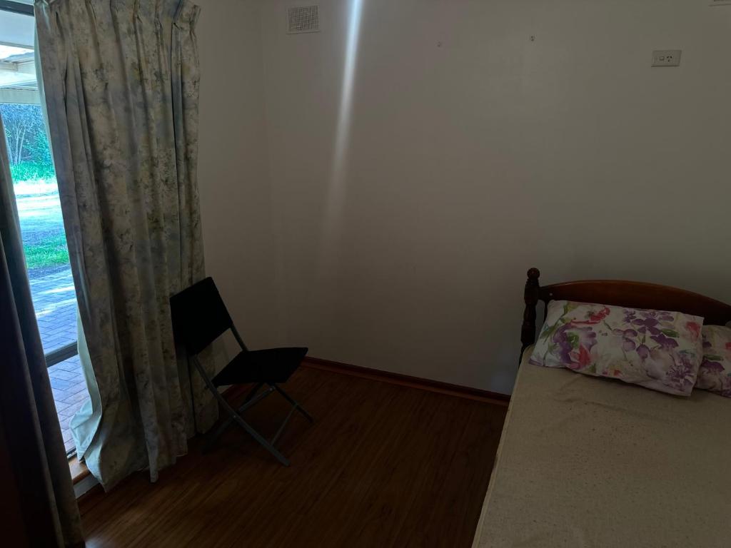 a bedroom with a bed and a chair next to a window at 333 chalkhill rd McLaren vale 5171 in McLaren Vale