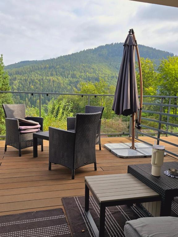 an outdoor deck with chairs and an umbrella at Loft Apart View & Wellness in Szczyrk
