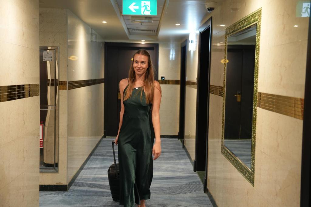 a woman walking down a hallway with a suitcase at AG Hotel in Abu Dhabi