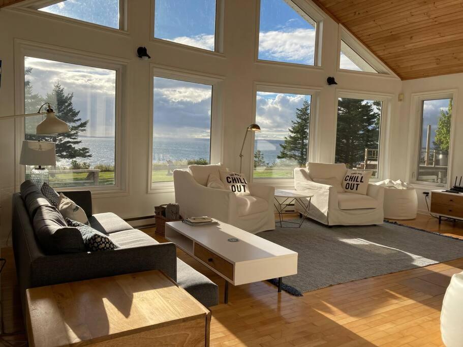 Una sala de estar con muebles blancos y grandes ventanales. en Private Waterfront Luxury with Hot Tub and Barrel Sauna, en Sydney Forks
