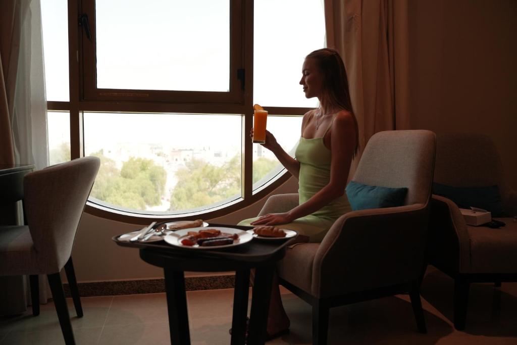 a woman standing in front of a window with a plate of food at AG Hotel in Abu Dhabi