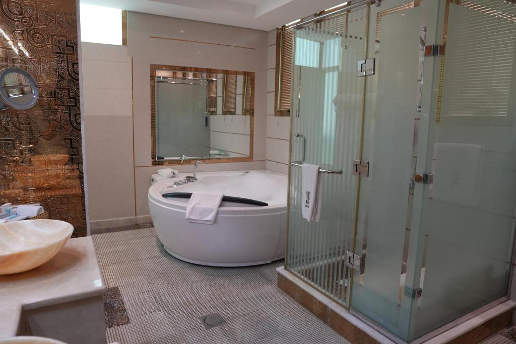 a bathroom with a tub and a glass shower at AG Hotel in Abu Dhabi