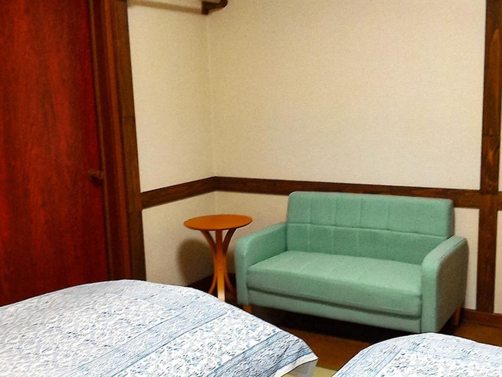 a bedroom with a green chair and a table at Pension Come Western-style room loft- Vacation STAY 14990 in Minami Uonuma