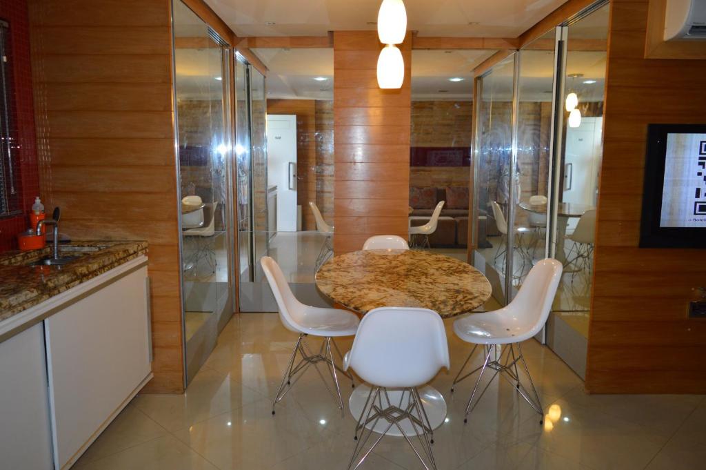 a kitchen with a marble table and white chairs at Apartamento Fortaleza Beira Mar in Fortaleza