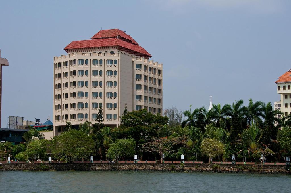 a large white building with a red roof next to a river at Vivanta Ernakulam, Marine Drive in Cochin