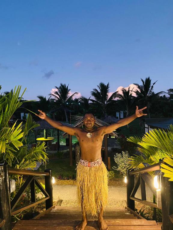 SigatokaSeatiki Resort Fiji的手臂伸出海滩的无衬衫男子