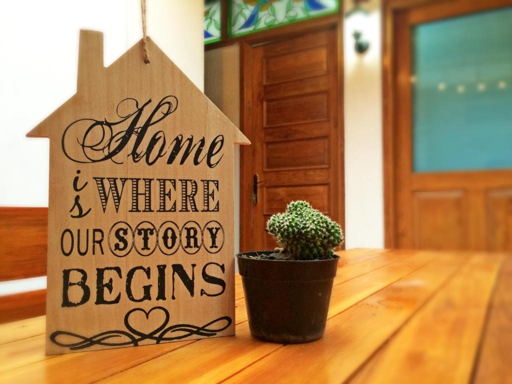 a wooden home and where our good begins sign next to a plant at Rumah Panjaitan in Yogyakarta