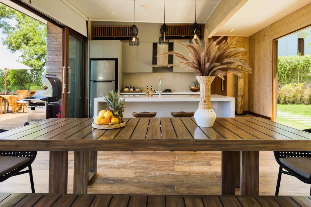 a kitchen and dining room with a wooden table at Selong Selo Resort and Residences in Selong Belanak