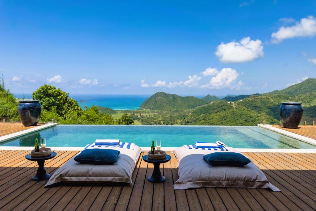 two beds on a deck next to a swimming pool at Selong Selo Resort and Residences in Selong Belanak