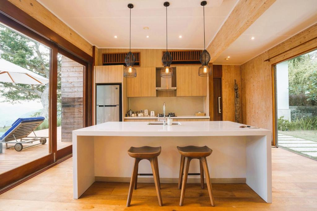 a kitchen with a large white island with two bar stools at Selong Selo Resort and Residences in Selong Belanak