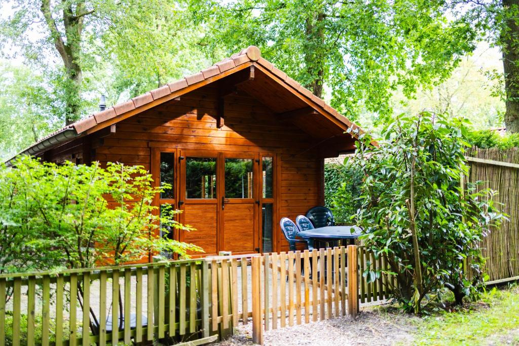 a small wooden cabin with a fence in front of it at Huisdiervriendelijk houten huisje in het groen in Epe