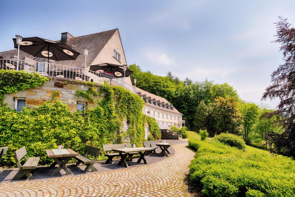 eine Reihe von Picknicktischen vor einem Gebäude in der Unterkunft Welcome Hotel Meschede Hennesee in Meschede