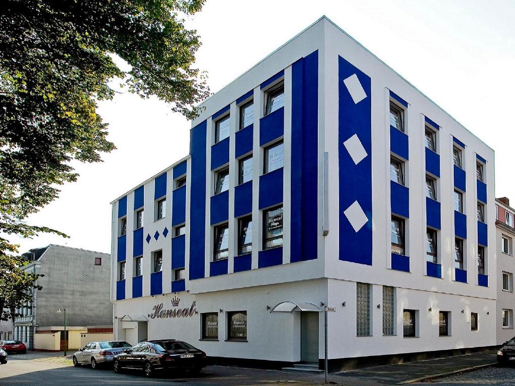 un edificio azul y blanco con coches aparcados en un aparcamiento en Gästehaus Hanseat, en Bremerhaven