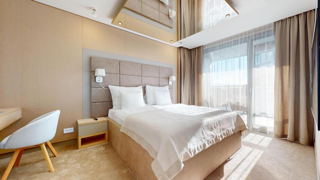 a bedroom with a bed and a chair and a window at Eurovea Tower Apartments in Petržalka