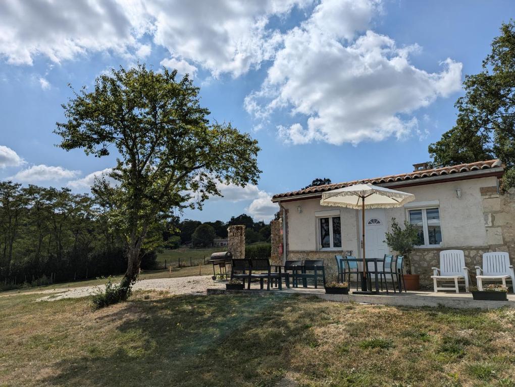 une maison avec une table, des chaises et un parasol dans l'établissement Petit gîte de charme Bichta Eder, à Magnac-Lavalette