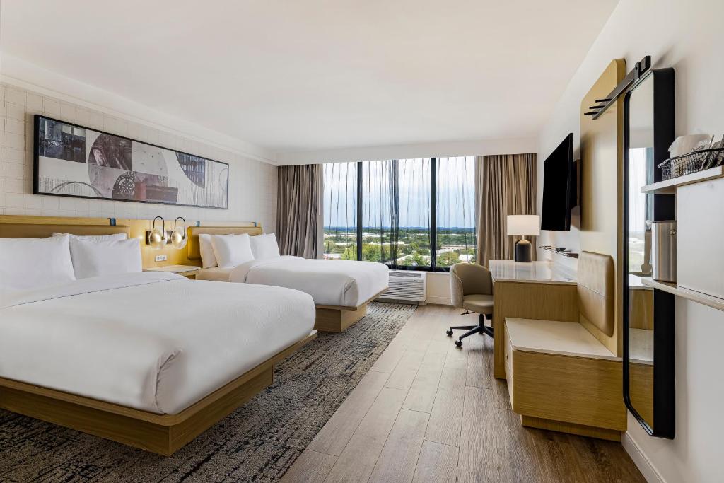 a hotel room with two beds and a desk at Hotel Preston Nashville Airport in Nashville