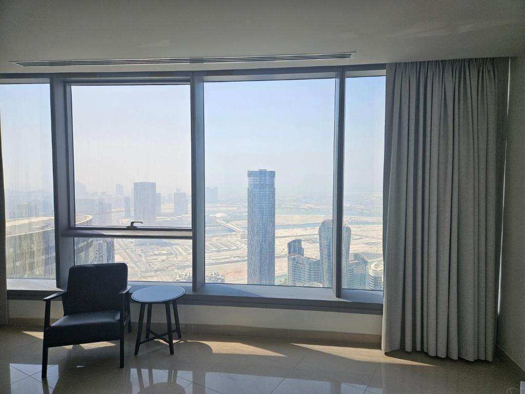 a room with a chair and a table in front of a window at C-Suite Views at Al Reem and Al Maryah Island in Abu Dhabi