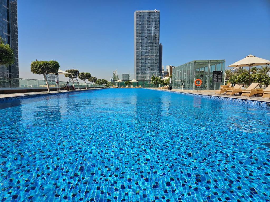 a large blue swimming pool with buildings in the background at C-Suite Views at Al Reem and Al Maryah Island in Abu Dhabi