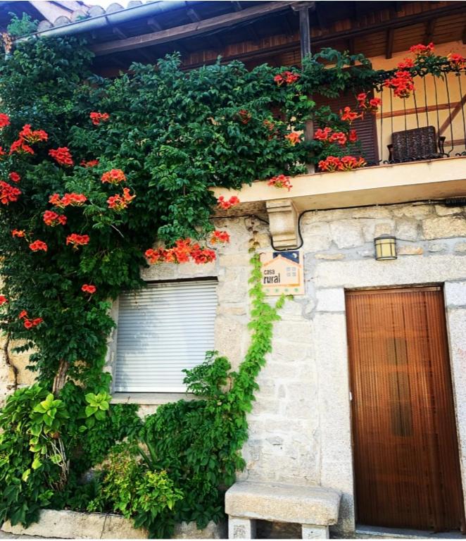 a building with flowers on the side of it at Casa Rural el Comercio Sierra de Francia in San Miguel de Valero