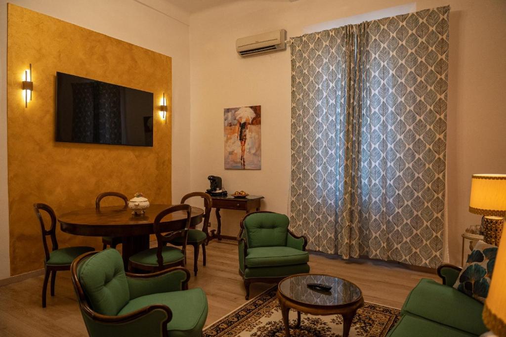a living room with a table and green chairs at Hotel Roma in Bologna