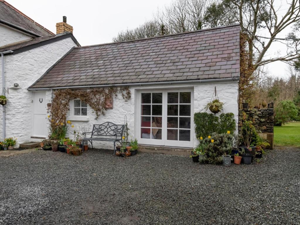 a white cottage with a bench in front of it at Secluded Holiday Home in Ceredigion with Garden in Pennant