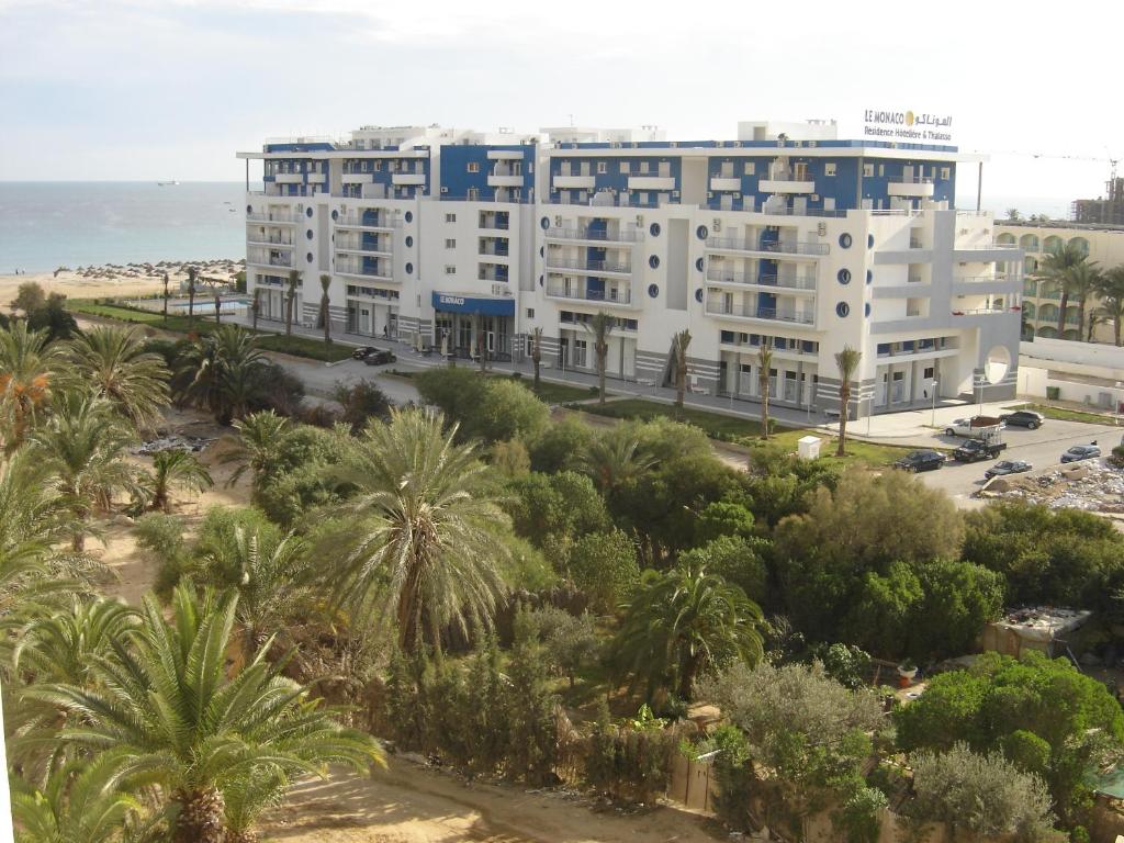 een groot wit gebouw met palmbomen en de oceaan bij Le Monaco Hôtel & Thalasso in Sousse