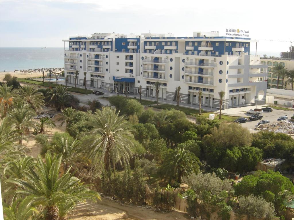 a large white building with palm trees and the ocean at Le Monaco Hôtel & Thalasso in Sousse