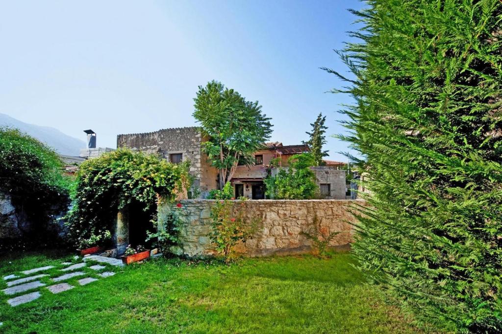 an old house behind a stone wall in a yard at Holiday home in the Archanes with a garden in Archanes