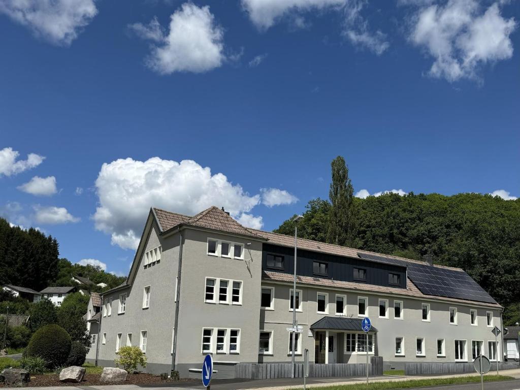 a large white building with trees in the background at Eifel Nationalpark Grand Lodge in Schleiden