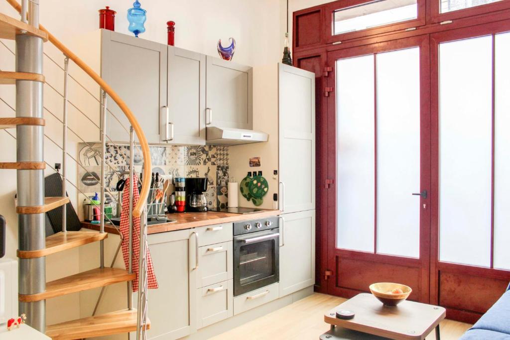une cuisine avec des placards blancs et un escalier en colimaçon dans l'établissement Charming apartment near Buttes-Chaumont, à Paris