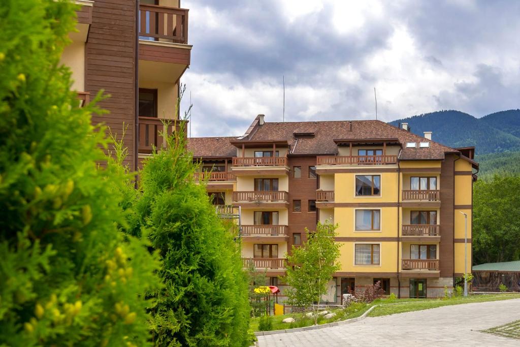 een groot appartementencomplex met bomen ervoor bij Pirin Sense apartment A11 in Bansko
