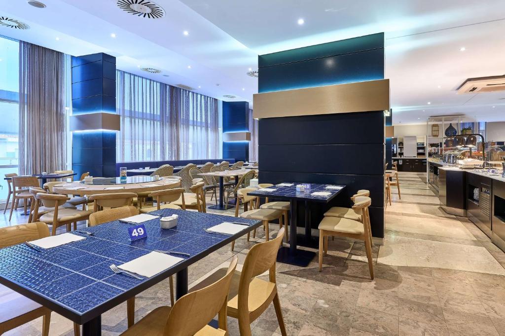 a restaurant with tables and chairs and a bar at TRYP by Wyndham Lisboa Caparica Mar in Costa da Caparica