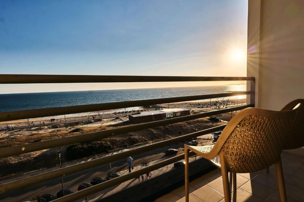 a room with a chair and a view of the ocean at TRYP by Wyndham Lisboa Caparica Mar in Costa da Caparica