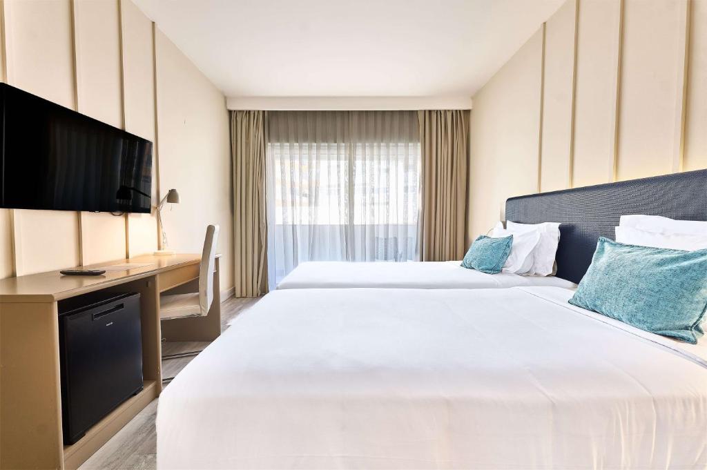 a hotel room with two beds and a television at TRYP by Wyndham Lisboa Caparica Mar in Costa da Caparica
