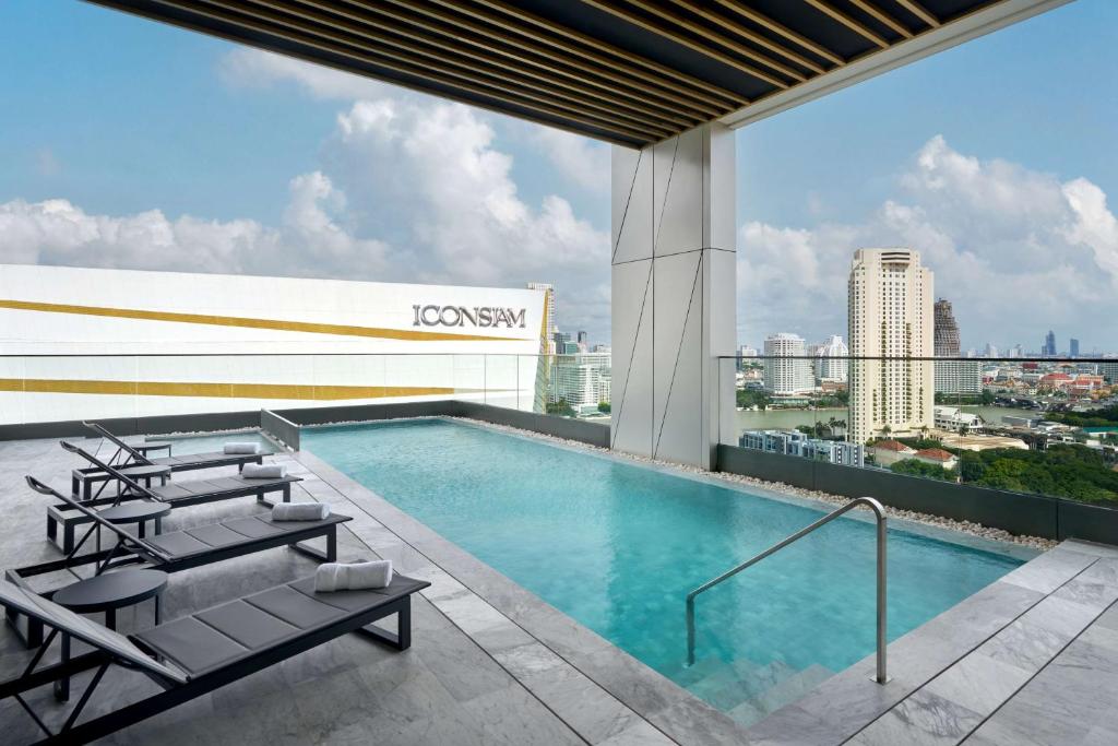 A rooftop pool deck offers loungers, a covered section, and views toward ICONSIAM and the surrounding city.