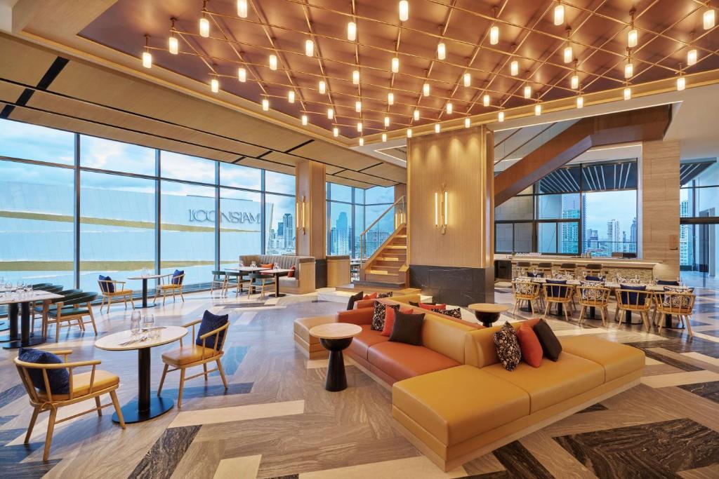 A spacious lounge and dining area with a large sofa, window seating and views across ICONSIAM.